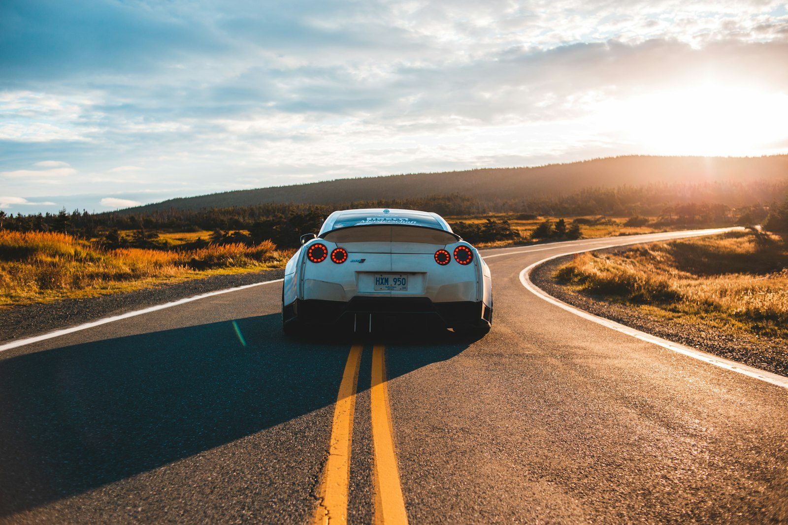 Car driving on an open road at sunset
